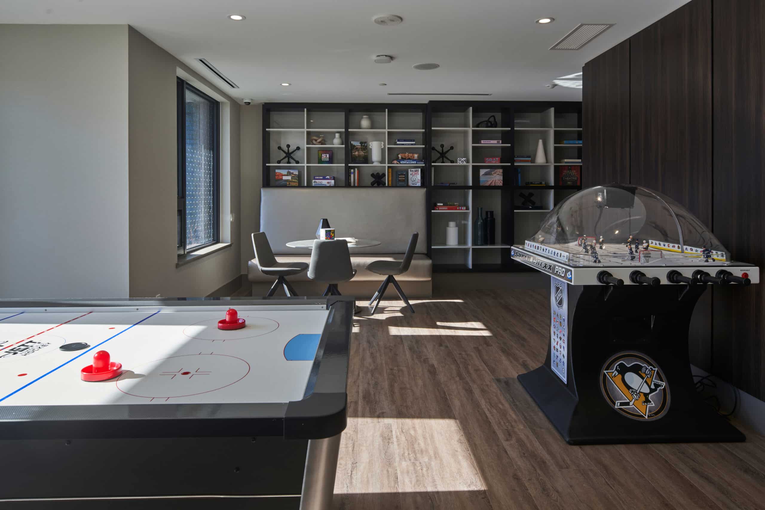 Ground-floor games room amenity with air hockey, dome hockey, and lounge seating, offering a condo-quality lifestyle at our Toronto apartments.