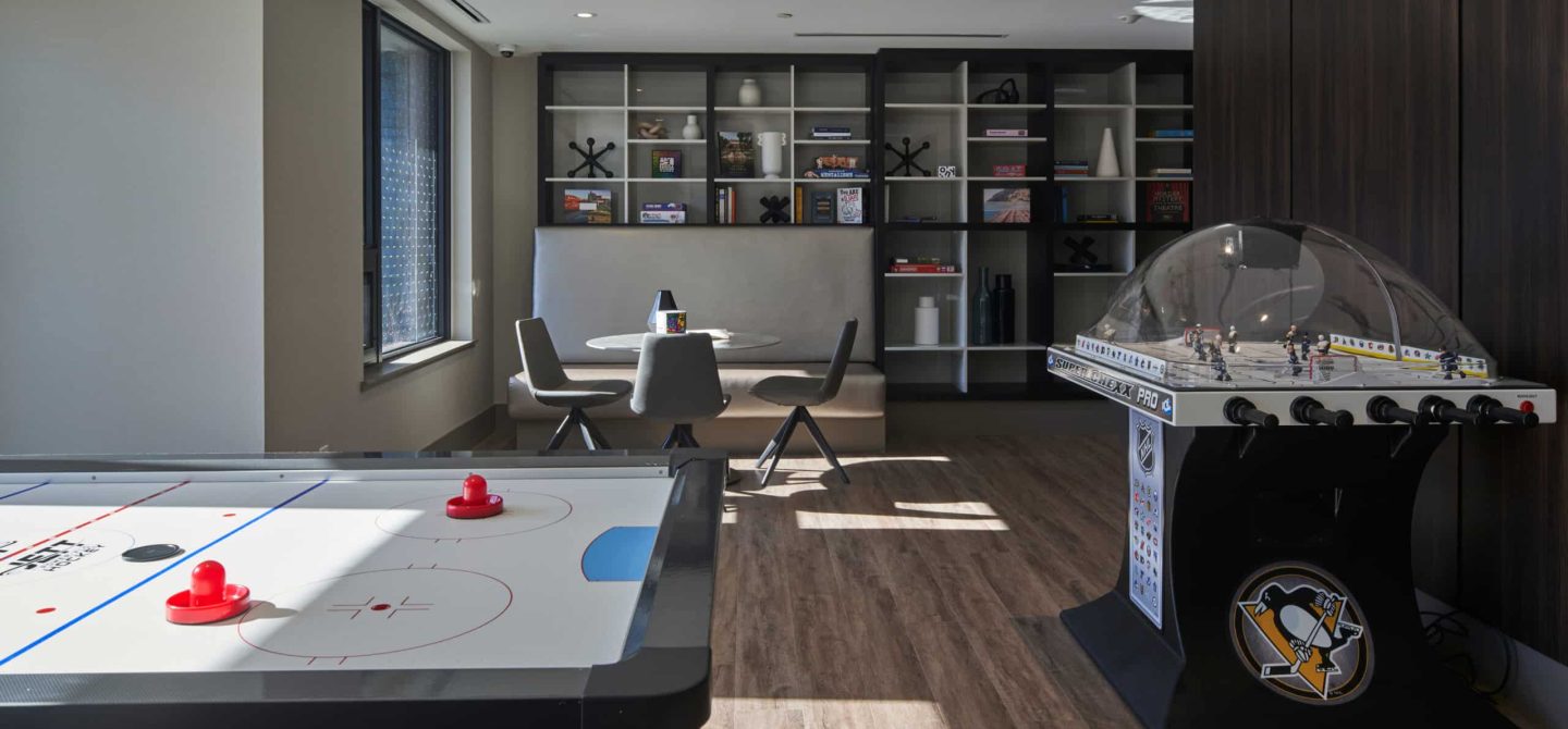 Ground-floor games room amenity with air hockey, dome hockey, and lounge seating, offering a condo-quality lifestyle at our Toronto apartments.