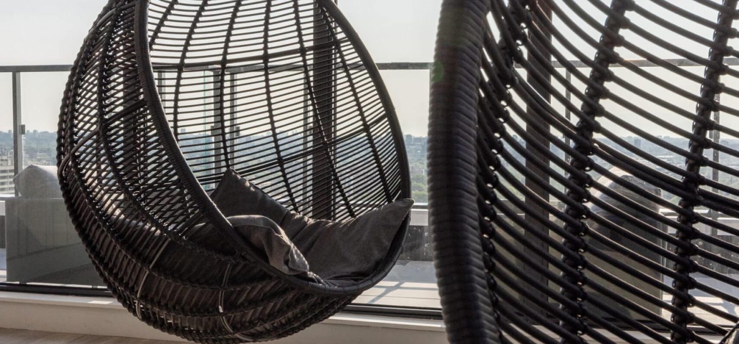 Close-up of stylish hanging wicker chairs on the outdoor terrace, providing a relaxing retreat for residents of our luxury apartments near Yonge and Eglinton.