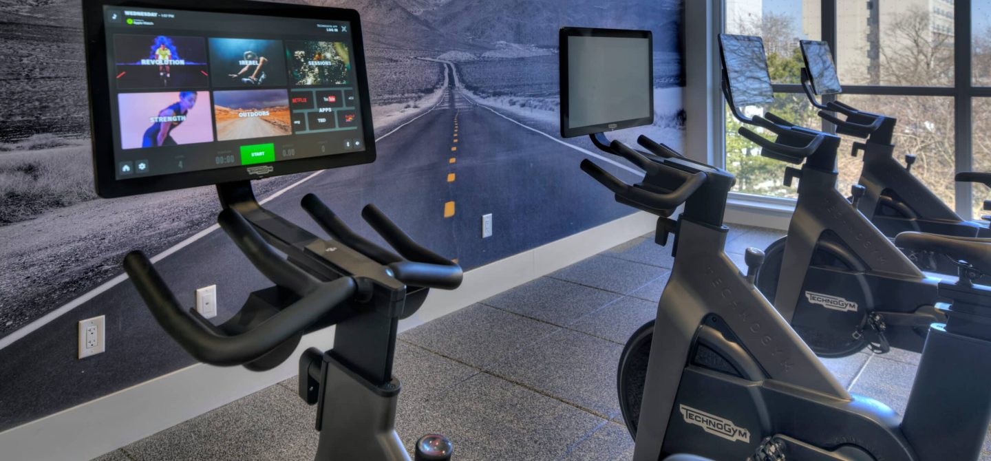 Dedicated spin and cardio studio with Technogym bikes and immersive screen, part of the extensive wellness amenities at The Whitney on Redpath.