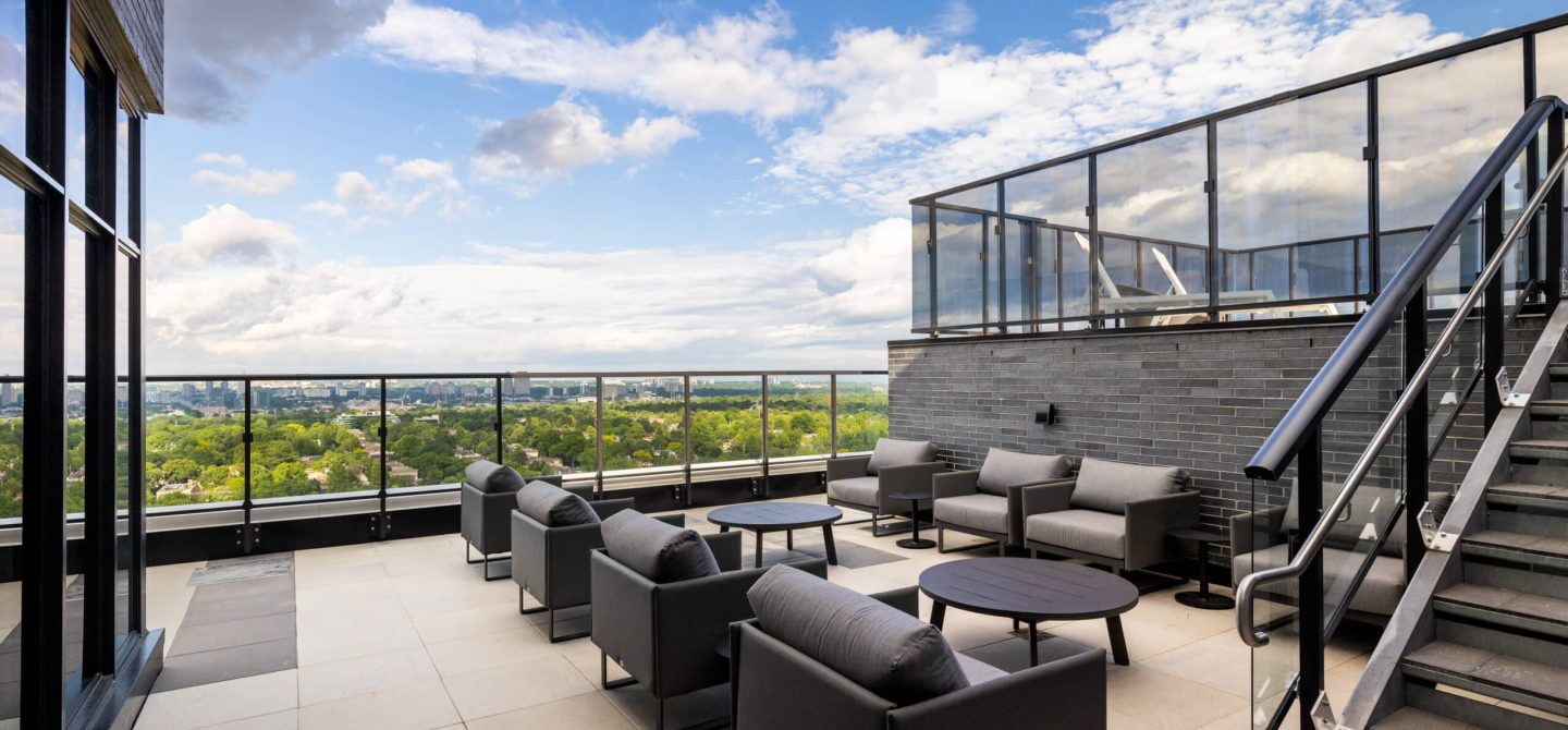 Expansive rooftop terrace with comfortable outdoor lounge seating and glass railings, offering panoramic views of Midtown Toronto at our luxury rental building.
