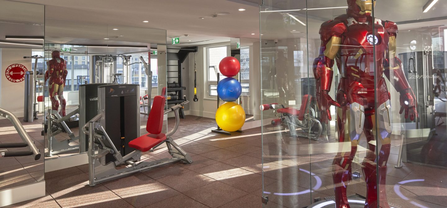 Fully equipped fitness studio featuring strength training machines and a life-size Iron Man display, a unique amenity at our Midtown Toronto apartments.