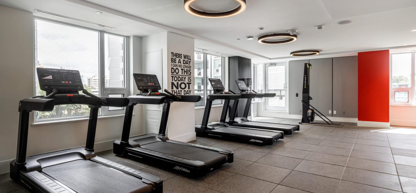 State-of-the-art fitness center featuring treadmills and motivational wall art, a premium amenity for residents of our Toronto luxury apartments.