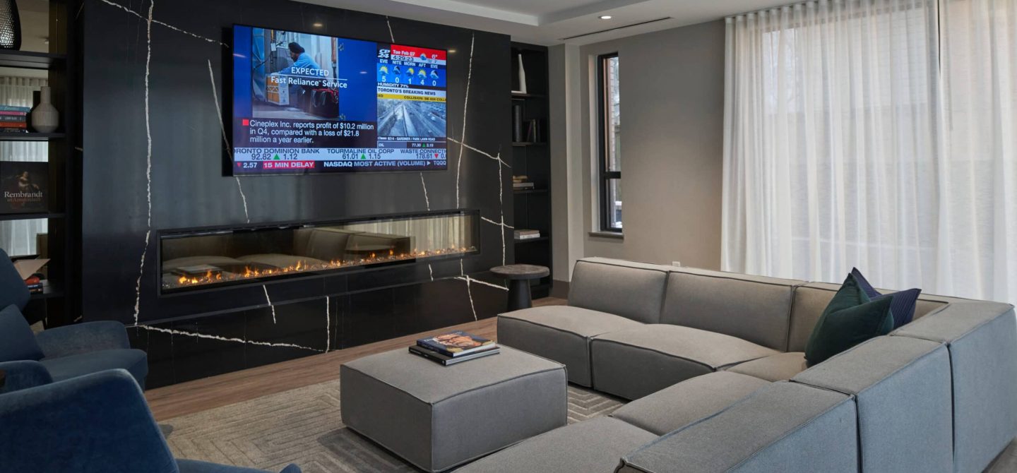 Beautifully appointed theatre lounge and entertainment space featuring a striking black marble fireplace for residents of The Whitney on Redpath.