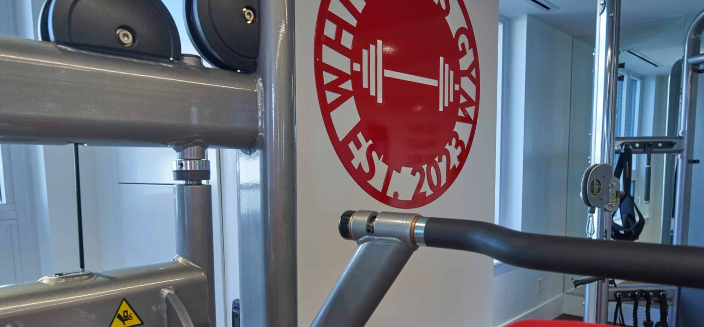 Close-up of a weight machine and the custom-designed gym wall logo, a part of the premium wellness centre in our luxury Toronto rental building.
